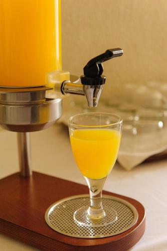 a glass of orange juice on a coaster with a juicer at Hotel Pappas in Kiáton