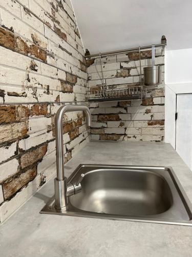 uma cozinha com um lavatório e uma parede de tijolos em La Casita del abuelo Javi em Cambados