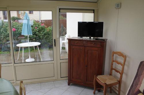 een woonkamer met een televisie, een tafel en een stoel bij CHAMBRES D'HÔTES chez réjane in Crasville