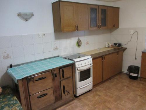La cuisine est équipée de placards en bois et d'une cuisinière blanche. dans l'établissement Apartma Vilma, à Kobarid