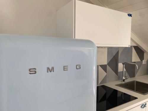 una cucina bianca con lavello e frigorifero di Diano Design&Suite Azur a Diano Marina