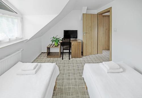 two beds in a room with a desk and a television at Dom Wczasowy Beskidy in Wisła