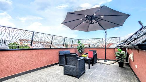 a patio with a table and an umbrella on a balcony at Spacious & attractive 600m-7minuta hoda od centra, mogucnost za parking-apartmani-nsmilos in Novi Sad
