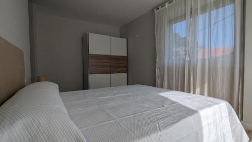 een slaapkamer met een wit bed en een raam bij Playa de Liméns in Cangas de Morrazo