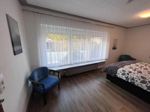 a bedroom with a bed and a chair and a window at Modern und Rustikal mit Kamin Ferienwohnung Kohlert in Bad Berleburg