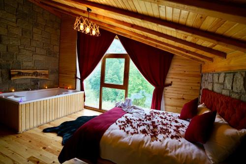 ein Schlafzimmer mit einem großen Bett und einer Badewanne in der Unterkunft DERE AĞZI TATİL KÖYÜ in Rize