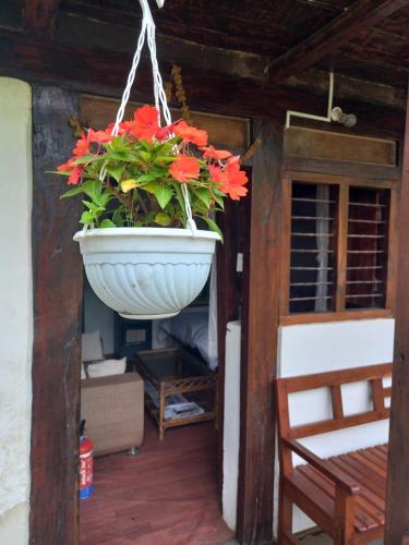 a pot of red flowers hanging from a porch at Riverside Homes in Deorāli