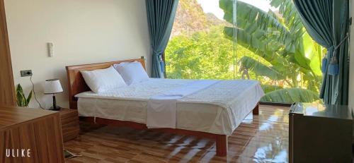 a bedroom with a bed and a large window at Phong Nha Moonlight Villas in Phong Nha