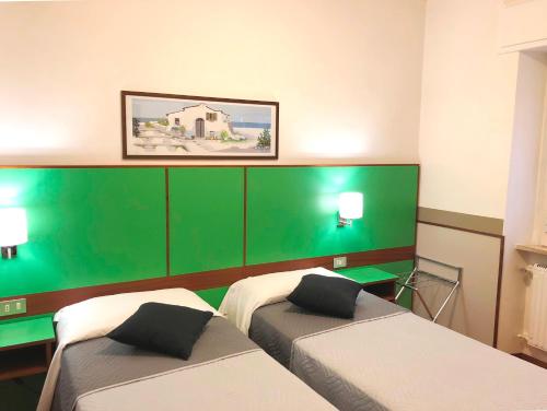two beds in a room with green and white at Hotel Signa in Perugia
