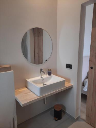 a bathroom with a white sink and a mirror at Komo Hill Stays - guestroom Komo Cosy in Kruisem