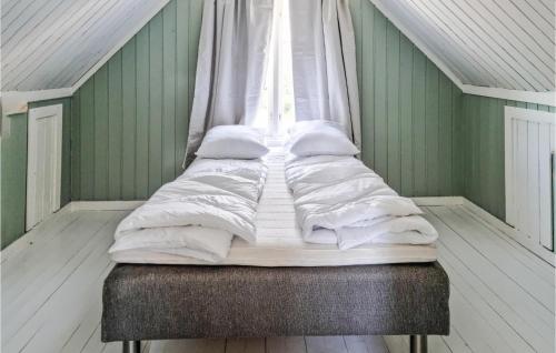 een bed met witte lakens en kussens in een kamer bij Stunning Home In Risr With Kitchen in Risør