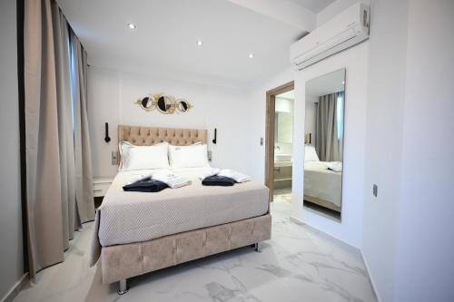 a white bedroom with a bed and a mirror at ROYAL VIEW VILLAS in Skiathos