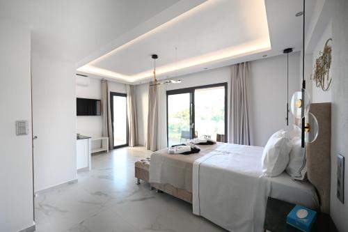 a white bedroom with a large bed and a kitchen at ROYAL VIEW VILLAS in Skiathos Town