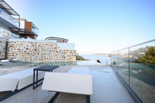 a balcony with white chairs and a view of the water at ROYAL VIEW VILLAS in Skiathos Town