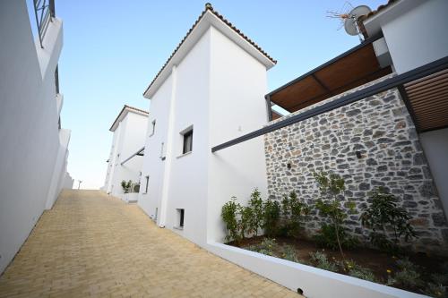 a narrow alleyway between two white buildings at ROYAL VIEW VILLAS in Skiathos Town