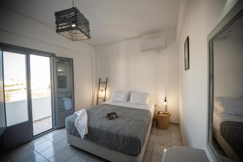 a white bedroom with a bed and a balcony at Villa Valvis in Perissa