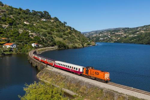 an orange and white train on tracks next to a lake at Chalé Caldas de Aregos in Caldas de Aregos