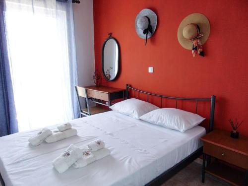 a bedroom with a white bed with a red wall at The Orange Cactus in Sparti