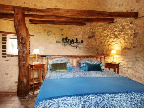 a bedroom with a blue bed in a stone wall at La Tour de rêves in Beaumont-la-Ronce