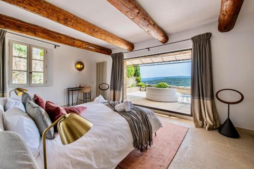 Un dormitorio con una cama grande y una ventana grande. en Le Mas Victoria, en Gordes