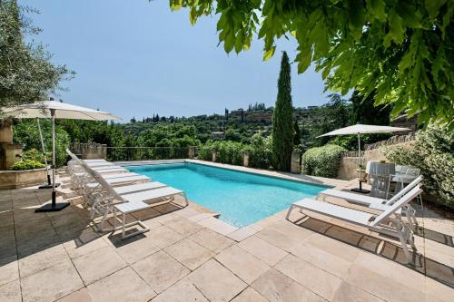 une piscine avec chaises longues et parasols dans l'établissement Le Mas Victoria, à Gordes