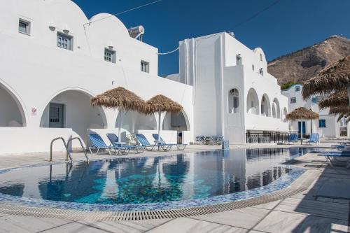 a swimming pool with chairs and white buildings at Villa Valvis in Perissa