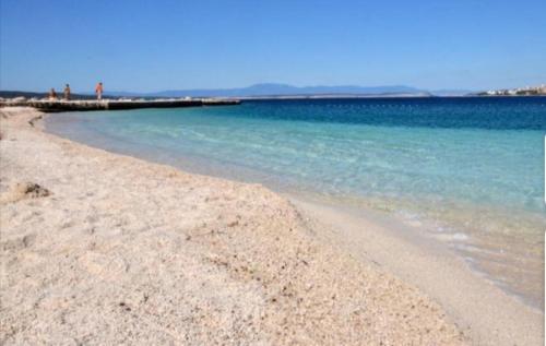 una playa de arena con agua azul y un muelle en AdriaLove, en Crikvenica
