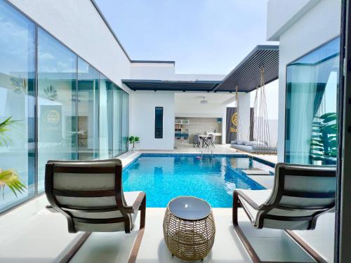 a house with a swimming pool with two chairs and a table at Rosella Chalet in Qurayyah