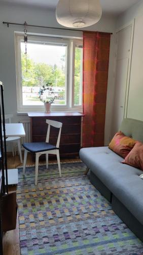 - un salon avec un lit, une chaise et une fenêtre dans l'établissement Peaceful and beautiful apartment in Hämeenlinna, à Hämeenlinna