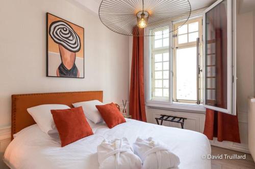 a bedroom with a white bed with pillows and a window at Suites Mana - MATAHINA avec VUE SUPERBE sur la Place DUCALE et Parking privé inclus in Charleville-Mézières