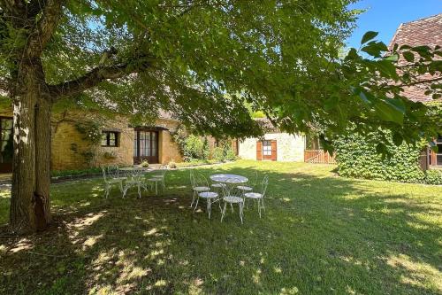 une table et des chaises sous un arbre dans une cour dans l'établissement La Couture, à Montferrand-du-Périgord