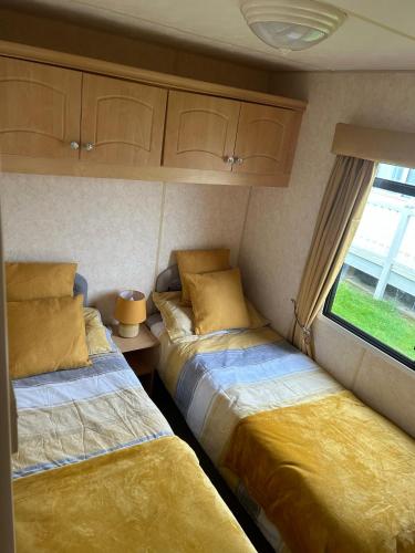 two beds in a small room with a window at 8 berth static caravan coral beach ingoldmells in Ingoldmells