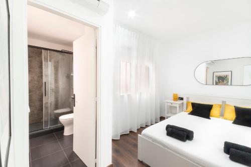 a white bedroom with a white bed and a bathroom at Design apartment plaça La font in Tarragona