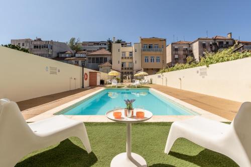 - une vue sur la piscine avec 2 chaises et une table dans l'établissement 733 Costa Cabral Metro Residence, à Porto