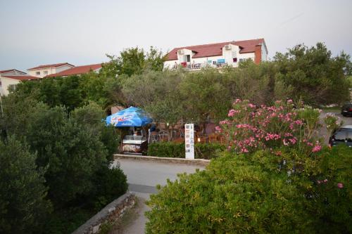 a bus driving down a road with a blue umbrella at Panorama Apartments in Povljana