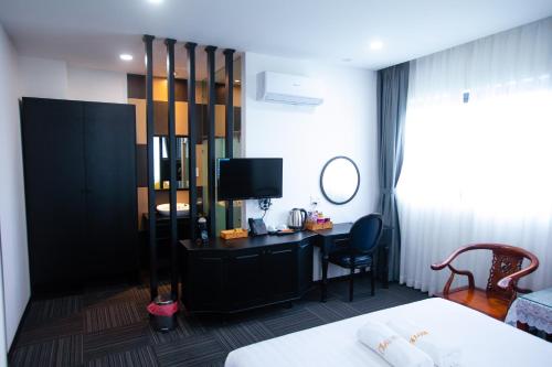 a hotel room with a bed and a desk with a television at ONE HOTEL in Vĩnh Long