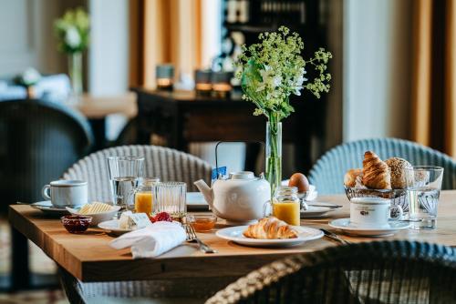 a table with breakfast foods and a vase of flowers at Niemeyers Romantik Posthotel in Faßberg