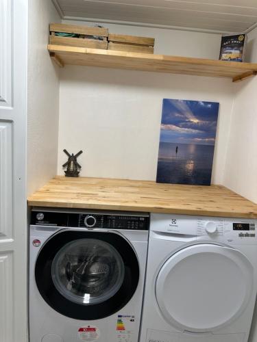 a washer and dryer in a room with a shelf at Charmerende stue lejlighed i centrum in Ringkøbing