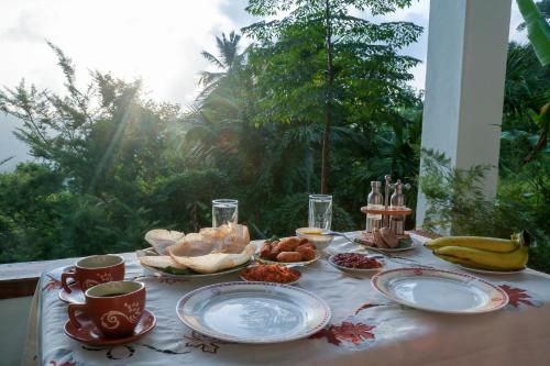 a table with plates of food on a table with a window at Hilltop Retreat Matale in Matale