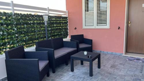 a patio with two chairs and a table and a wall of wine bottles at B&B Villa Anna in Sibari