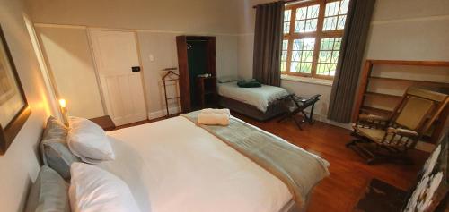 a bedroom with a large white bed and a window at Karoo Leeu Self Catering in Oudtshoorn
