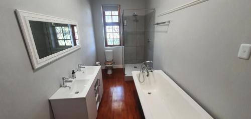 a white bathroom with two sinks and a bath tub at Karoo Leeu Self Catering in Oudtshoorn