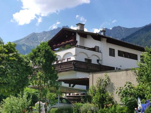 un bâtiment avec un balcon et des montagnes en arrière-plan dans l'établissement Alpendohle Apartments Innsbruck, à Innsbruck