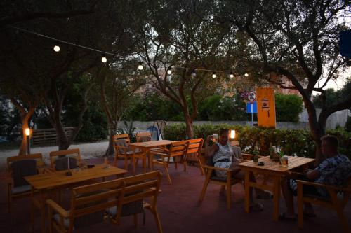 two people sitting at tables in a restaurant at night at Panorama Apartments in Povljana