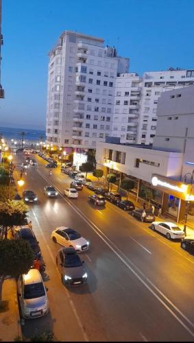 a busy city street with cars parked in front of buildings at Apparemment tanger enface hôtel el oumnia puerto in Tangier
