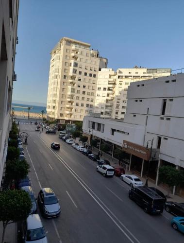 a city street with cars parked in front of buildings at Apparemment tanger enface hôtel el oumnia puerto in Tangier