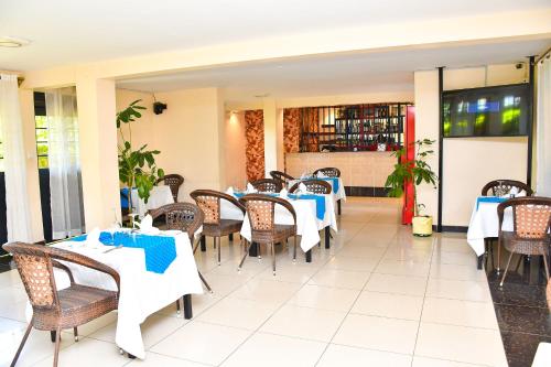 a restaurant with tables and chairs with blue napkins at Divine Homes Resort Kisumu in Kisumu