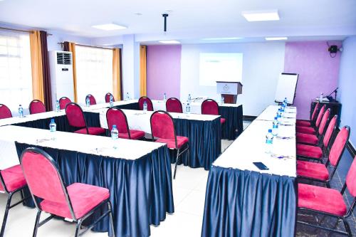 a conference room with tables and red chairs at Divine Homes Resort Kisumu in Kisumu