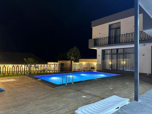 a swimming pool in front of a house at night at White Villa Ismayilli in İsmayıllı