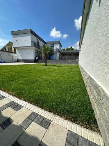 a grassy yard next to a building with a tree at White Villa Ismayilli in İsmayıllı